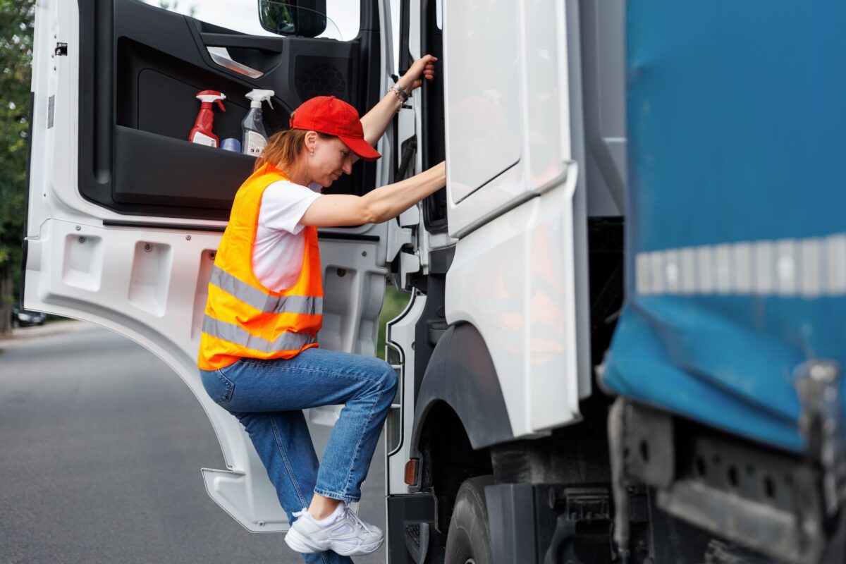 Young female 18-wheeler driver climbing into her truck